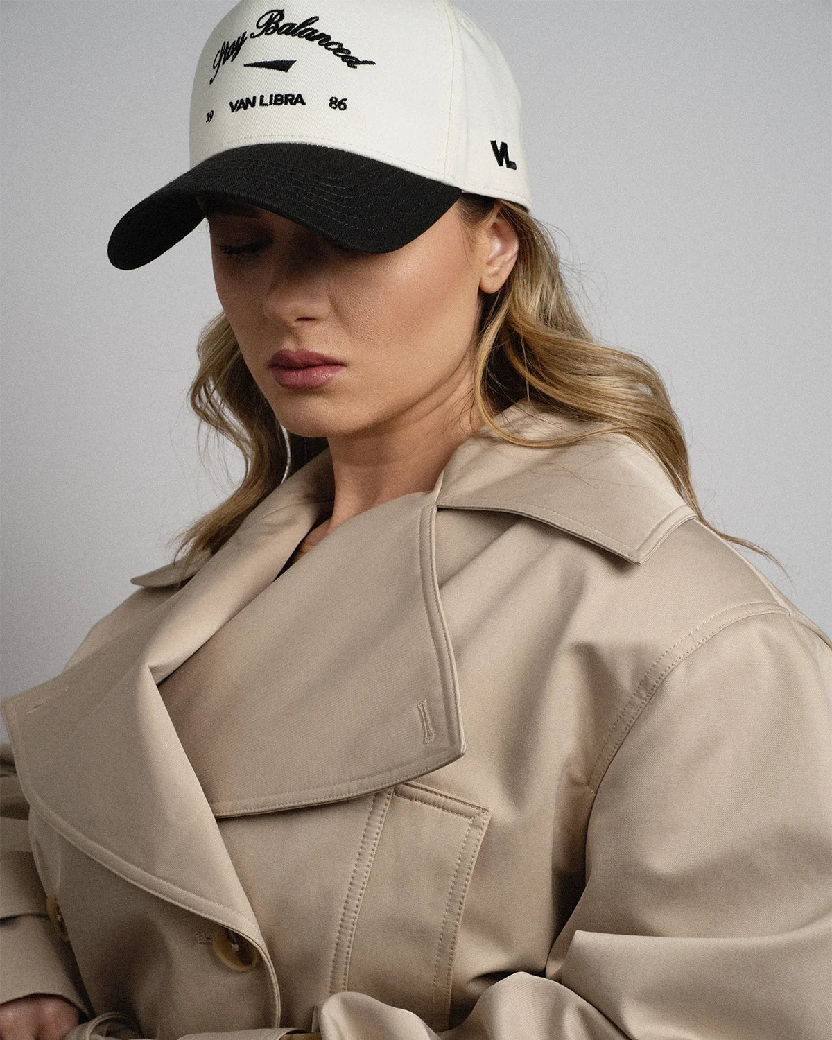 Van Libra Bone/Carbon (cream and dark gray) structured cap with bone colored crown and carbon colored brim. Features black embroidered text “Stay Balanced” with abstract triangle graphic on the front, “1986” and “VAN LIBRA” details, and “VL” stitched on the side, finished with an adjustable carbon colored snapback closure at the back.