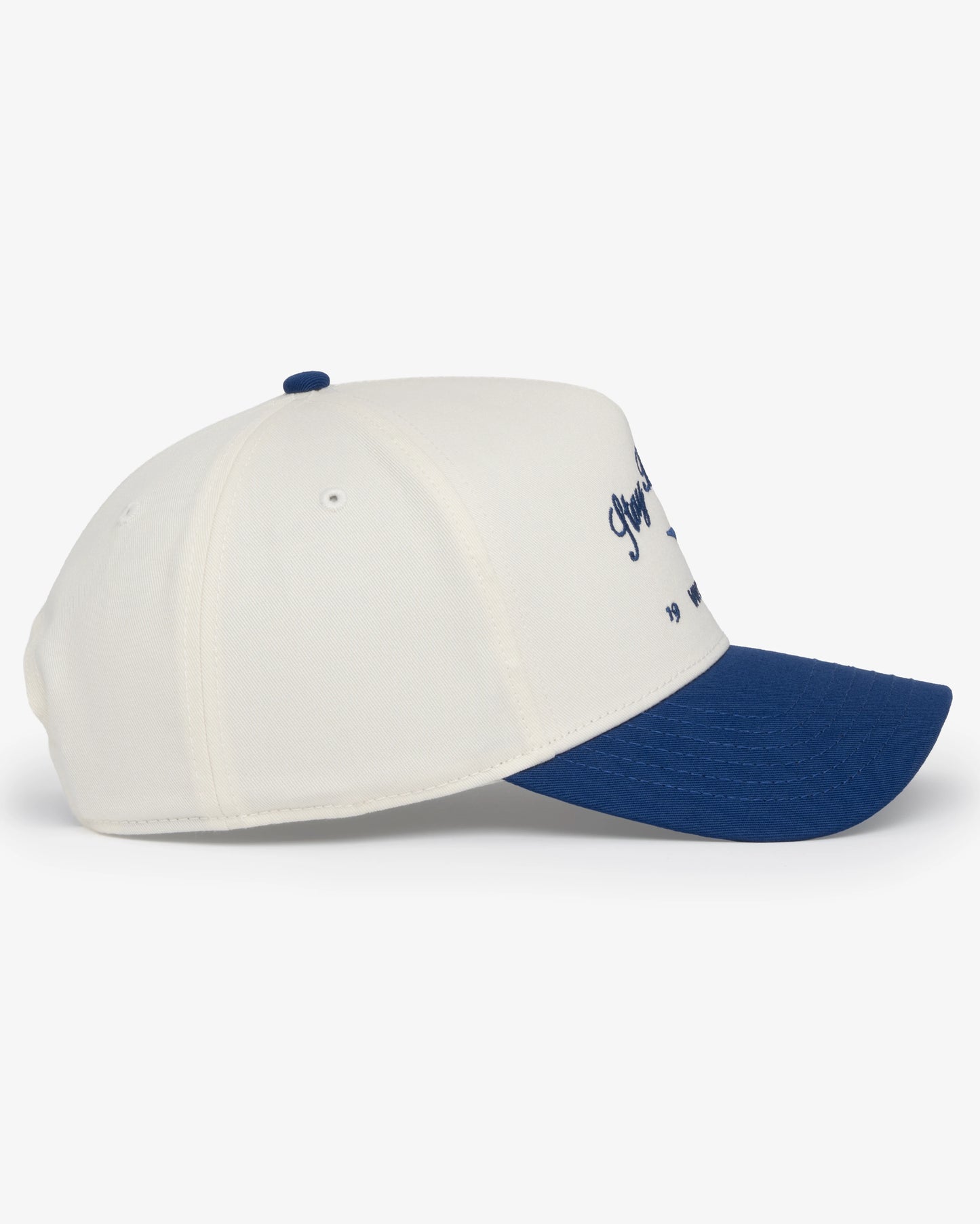 Van Libra Bone/Indigo (cream and blue) structured cap with bone colored crown and indigo colored brim. Features blue embroidered text “Stay Balanced” with abstract triangle graphic on the front, “1986” and “VAN LIBRA” details, and “VL” stitched on the side, finished with an adjustable indigo snapback closure at the back.