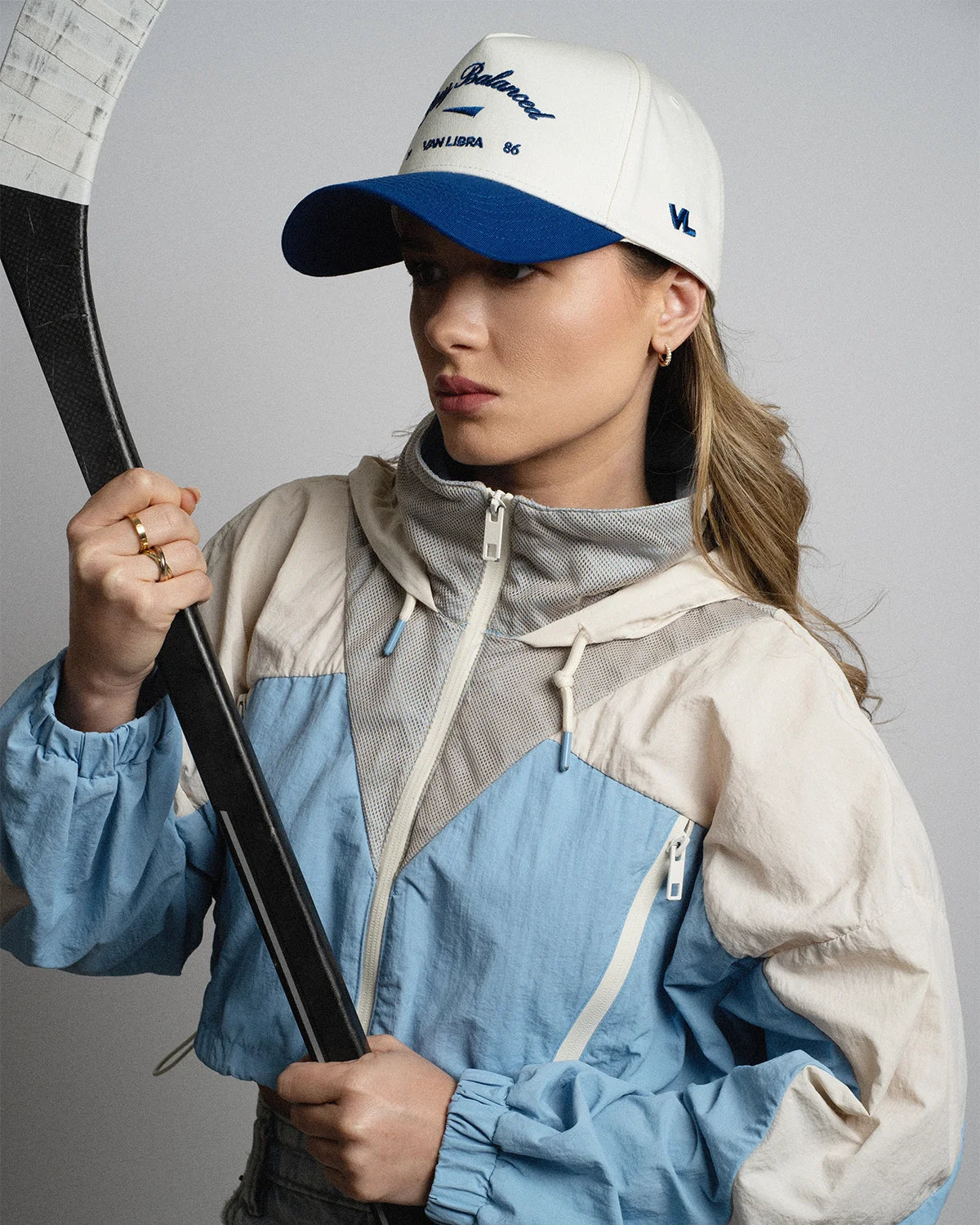Van Libra Bone/Indigo (cream and blue) structured cap with bone colored crown and indigo colored brim. Features blue embroidered text “Stay Balanced” with abstract triangle graphic on the front, “1986” and “VAN LIBRA” details, and “VL” stitched on the side, finished with an adjustable indigo snapback closure at the back.