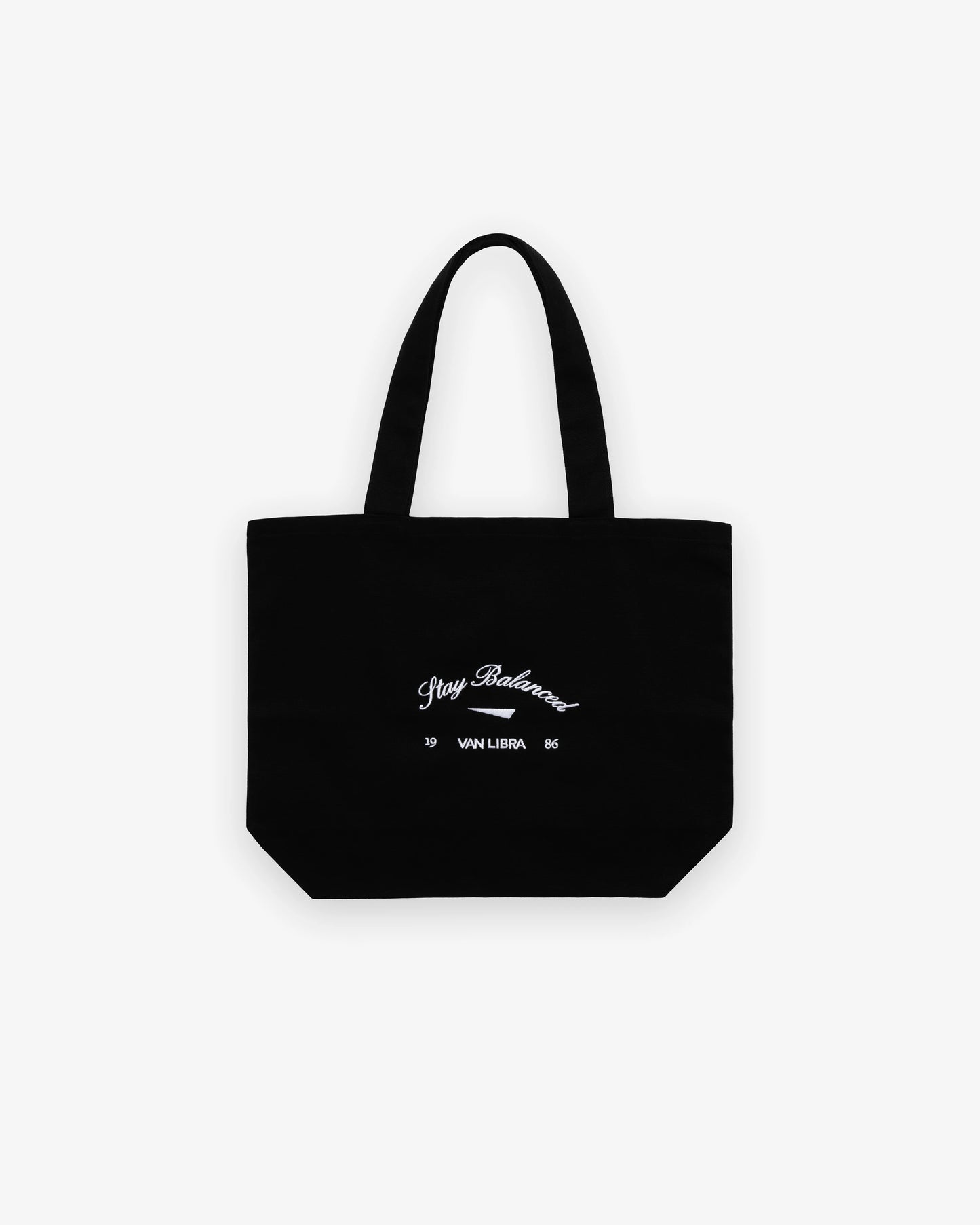 Van Libra Blackwood (black) canvas tote bag with white embroidery. Features “Stay Balanced” text above an abstract triangle graphic, with “VAN LIBRA” and the numbers “19” and “86” stitched below.