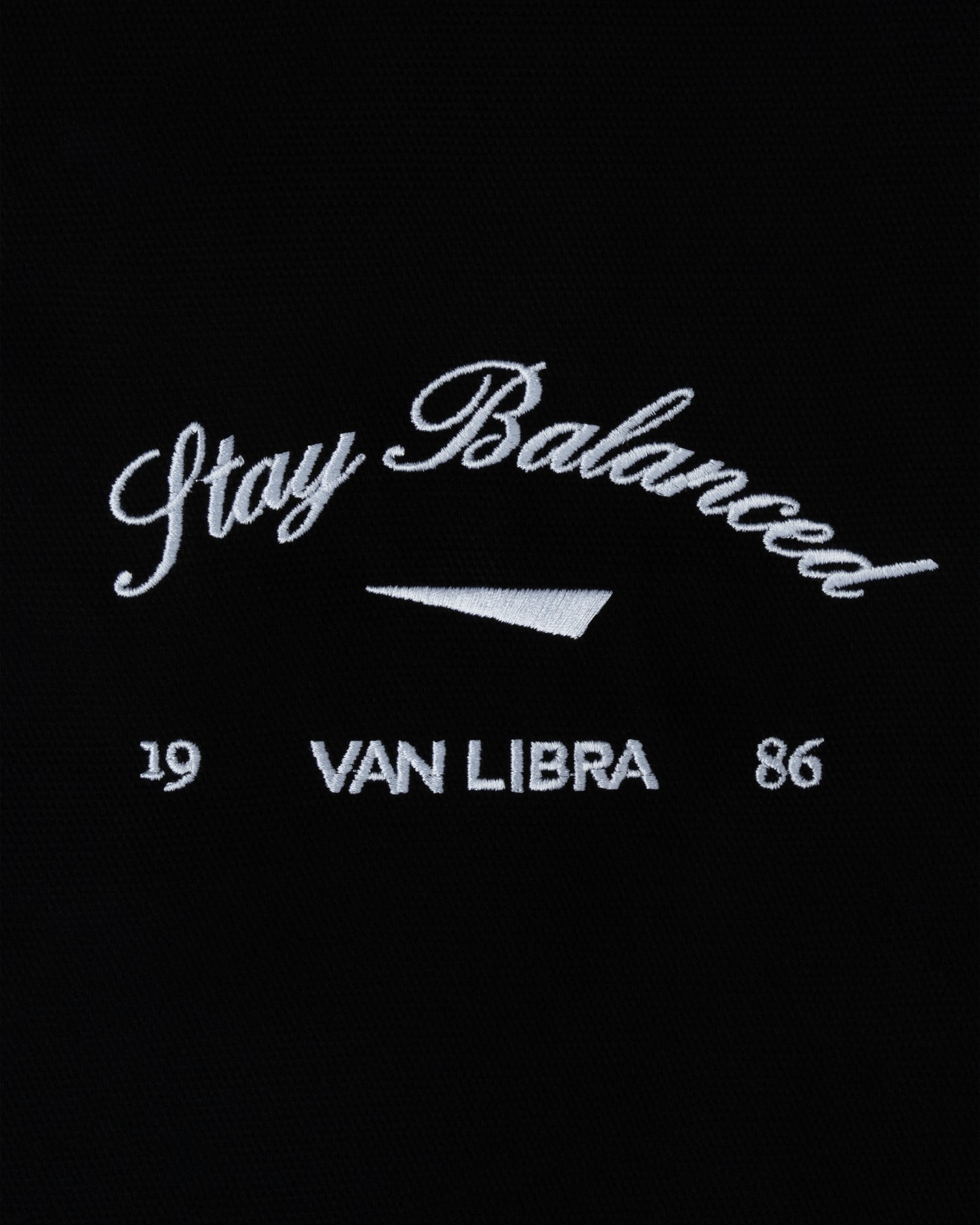 Van Libra Blackwood (black) canvas tote bag with white embroidery. Features “Stay Balanced” text above an abstract triangle graphic, with “VAN LIBRA” and the numbers “19” and “86” stitched below.