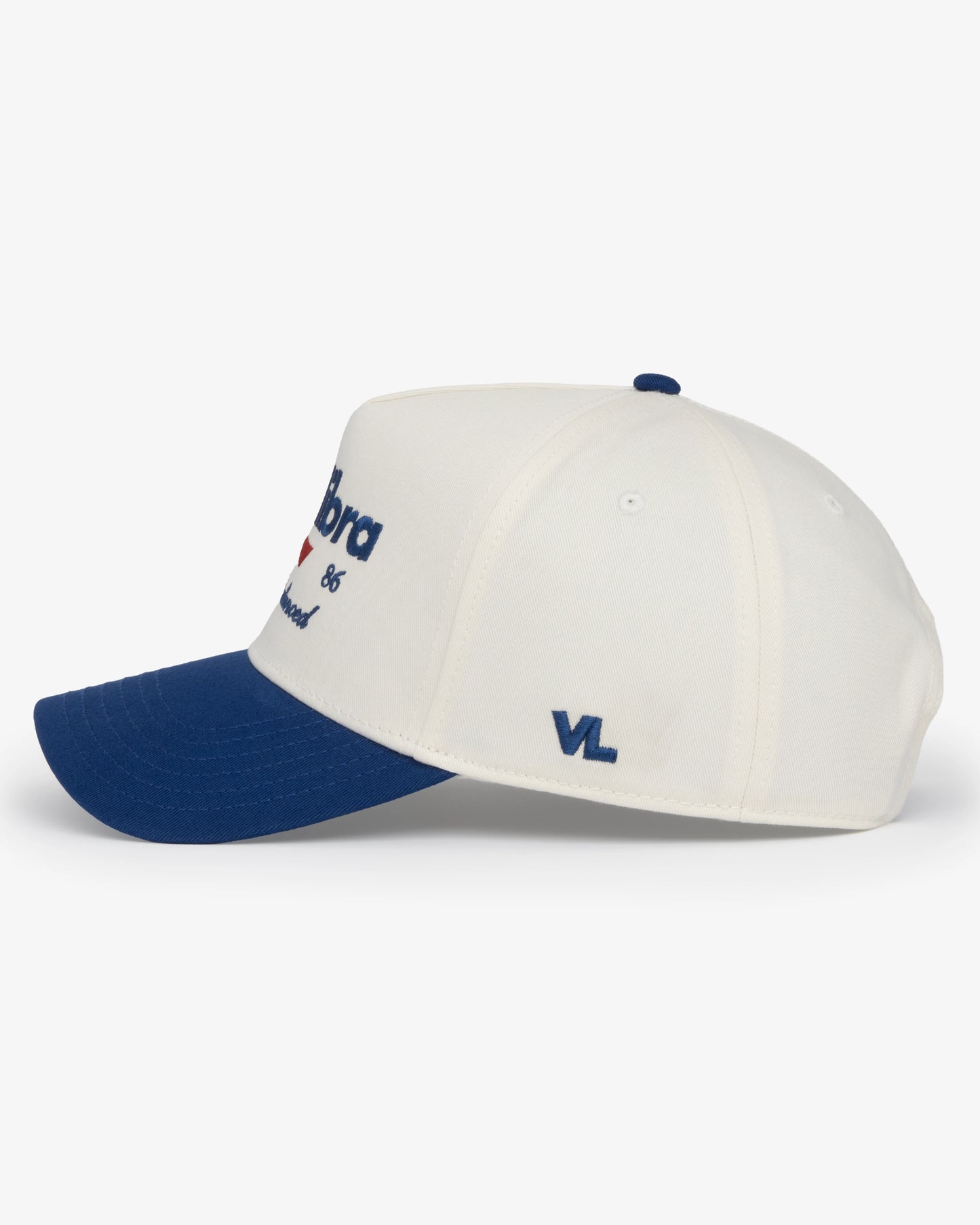 Van Libra Bone/Indigo (cream and blue) structured cap with bone colored crown and indigo colored brim. Features blue embroidered text “van libra” with red abstract triangle graphic on the front, blue “1986” and “Stay Balanced” lettering on the front, plus “VL” stitched on the side, finished with an adjustable indigo snapback closure at the back.