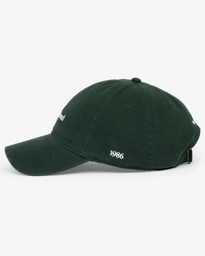 Van Libra Forest (dark green) dad hat with white embroidered text “Stay Balanced” on the front, “1986” stitched on the side, and “VAN LIBRA” on the back above an adjustable strap with brass buckle.