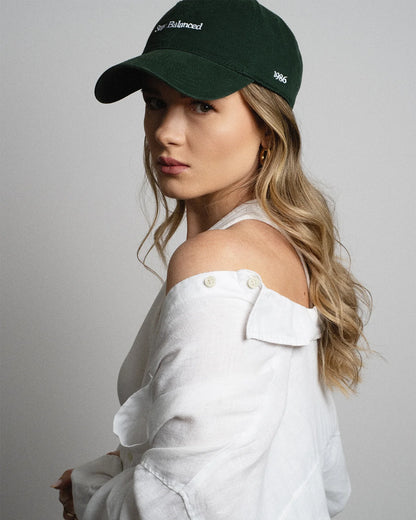 Van Libra Forest (dark green) dad hat with white embroidered text “Stay Balanced” on the front, “1986” stitched on the side, and “VAN LIBRA” on the back above an adjustable strap with brass buckle.