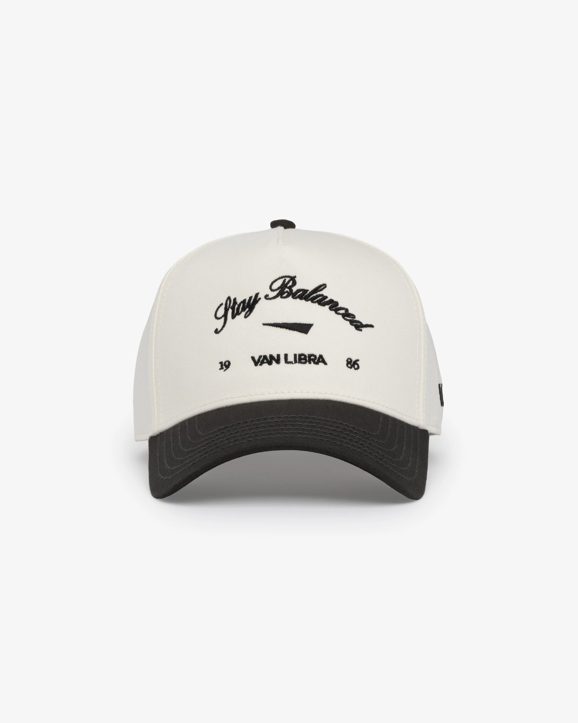 Van Libra Bone/Carbon (cream and dark gray) structured cap with bone colored crown and carbon colored brim. Features black embroidered text “Stay Balanced” with abstract triangle graphic on the front, “1986” and “VAN LIBRA” details, and “VL” stitched on the side, finished with an adjustable carbon colored snapback closure at the back.