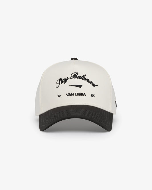 Van Libra Bone/Carbon (cream and dark gray) structured cap with bone colored crown and carbon colored brim. Features black embroidered text “Stay Balanced” with abstract triangle graphic on the front, “1986” and “VAN LIBRA” details, and “VL” stitched on the side, finished with an adjustable carbon colored snapback closure at the back.