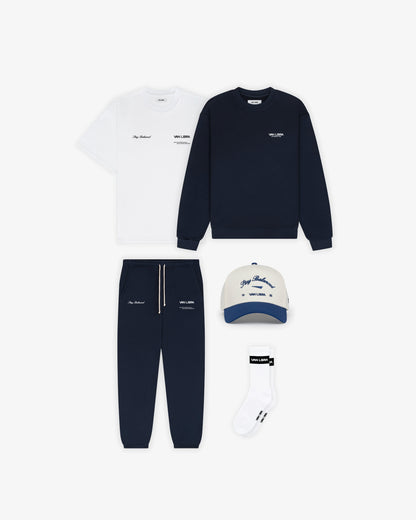 Van Libra Bone/Indigo (cream and blue) structured cap with bone colored crown and indigo colored brim. Features blue embroidered text “Stay Balanced” with abstract triangle graphic on the front, “1986” and “VAN LIBRA” details, and “VL” stitched on the side, finished with an adjustable indigo snapback closure at the back.