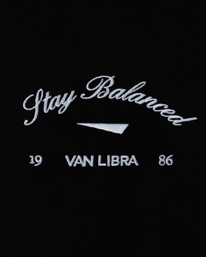 Van Libra Blackwood (black) canvas tote bag with white embroidery. Features “Stay Balanced” text above an abstract triangle graphic, with “VAN LIBRA” and the numbers “19” and “86” stitched below.