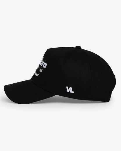 Van Libra Blackwood (black) structured cap with blackwood colored crown and brim. Features white embroidered text “van libra” with abstract triangle graphic on the front, “1986” and “Stay Balanced” lettering on the front, plus “VL” stitched on the side, finished with an adjustable blackwood snapback closure at the back.