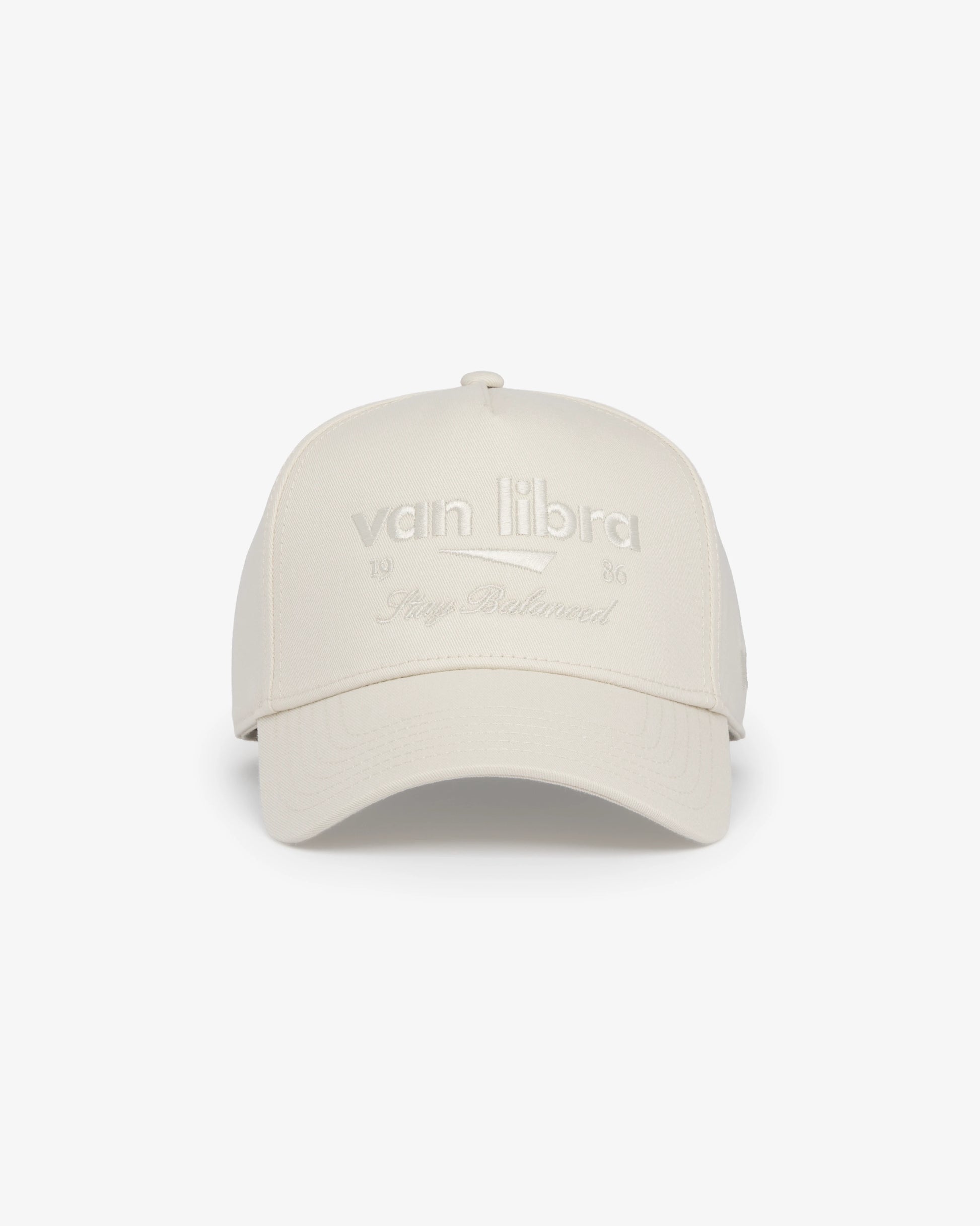 Van Libra Ivory (cream) structured cap with ivory crown and brim. Features cream colored embroidered text “van libra” with abstract triangle graphic on the front, “1986” and “Stay Balanced” lettering on the front, plus “VL” stitched on the side, finished with an adjustable ivory snapback closure at the back.