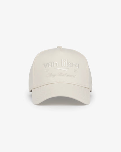 Van Libra Ivory (cream) structured cap with ivory crown and brim. Features cream colored embroidered text “van libra” with abstract triangle graphic on the front, “1986” and “Stay Balanced” lettering on the front, plus “VL” stitched on the side, finished with an adjustable ivory snapback closure at the back.