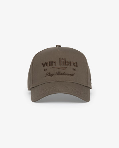 Van Libra Umber (brown) structured cap with umber colored crown and brim. Features brown embroidered text “van libra” with abstract triangle graphic on the front, “1986” and “Stay Balanced” lettering on the front, plus “VL” stitched on the side, finished with an adjustable umber snapback closure at the back.